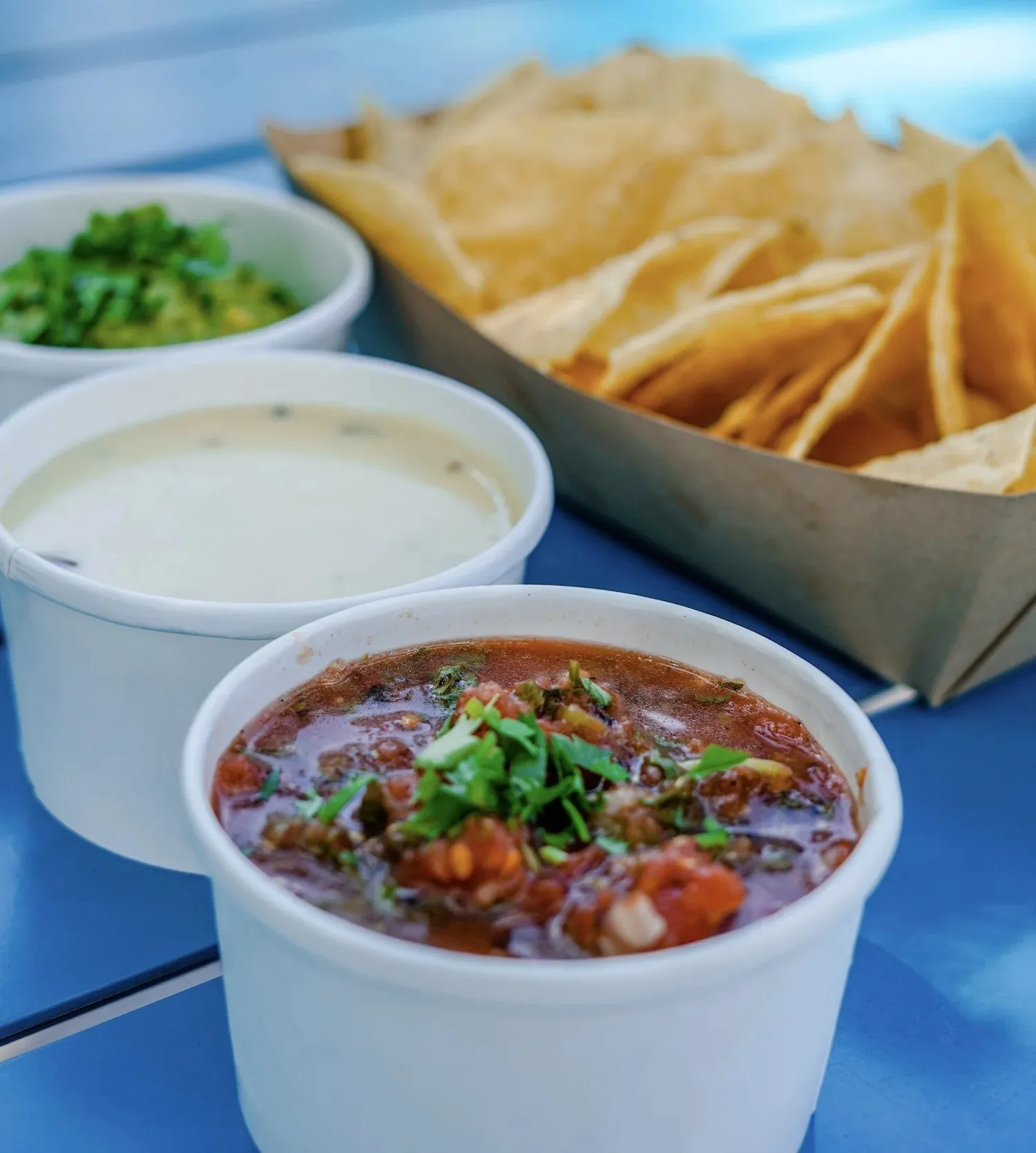 Tortilla chips with cups of guacamole, queso and salsa