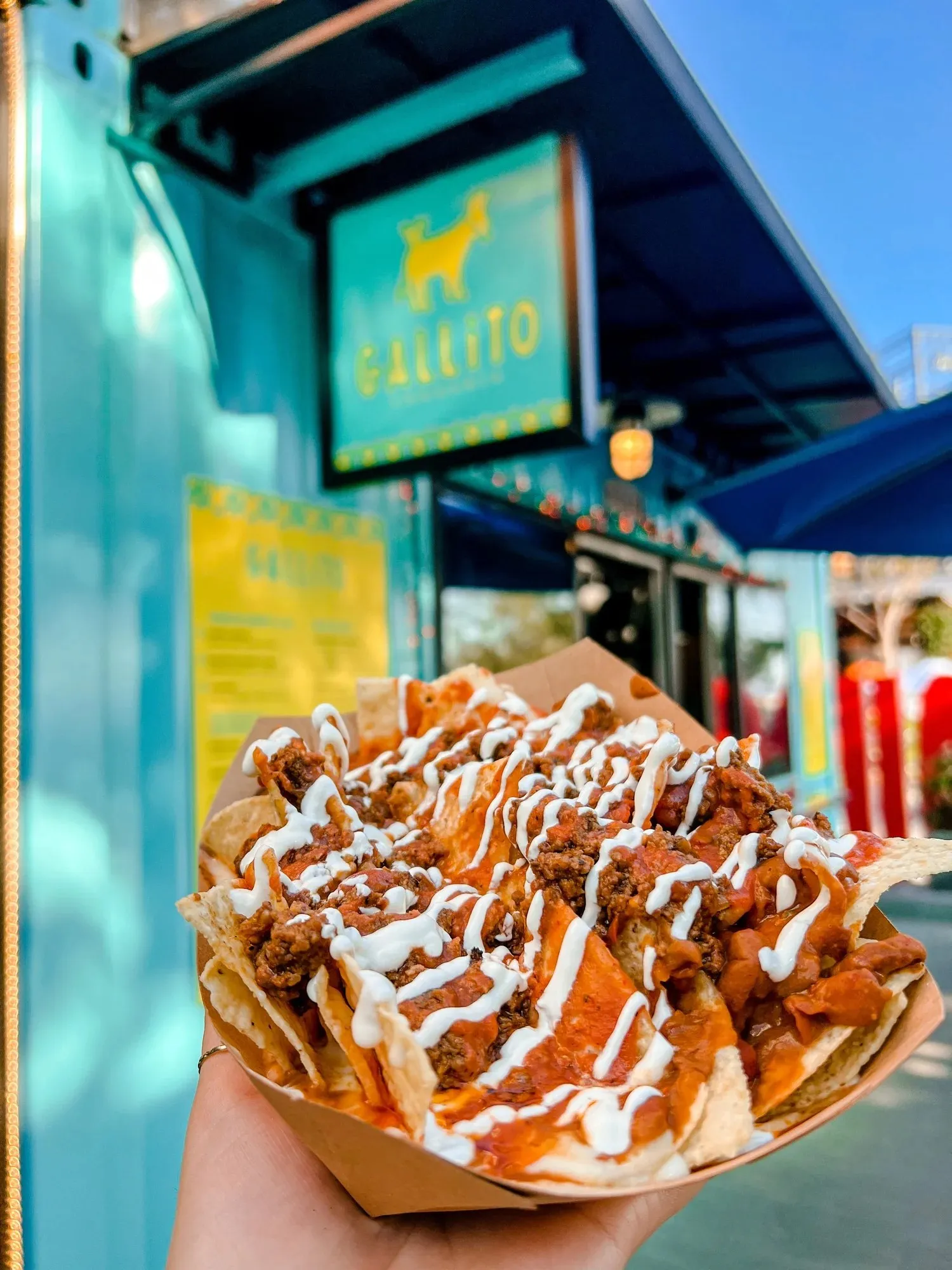 A boat of nachos with queso, beans and sour cream in front of the Gallito stand